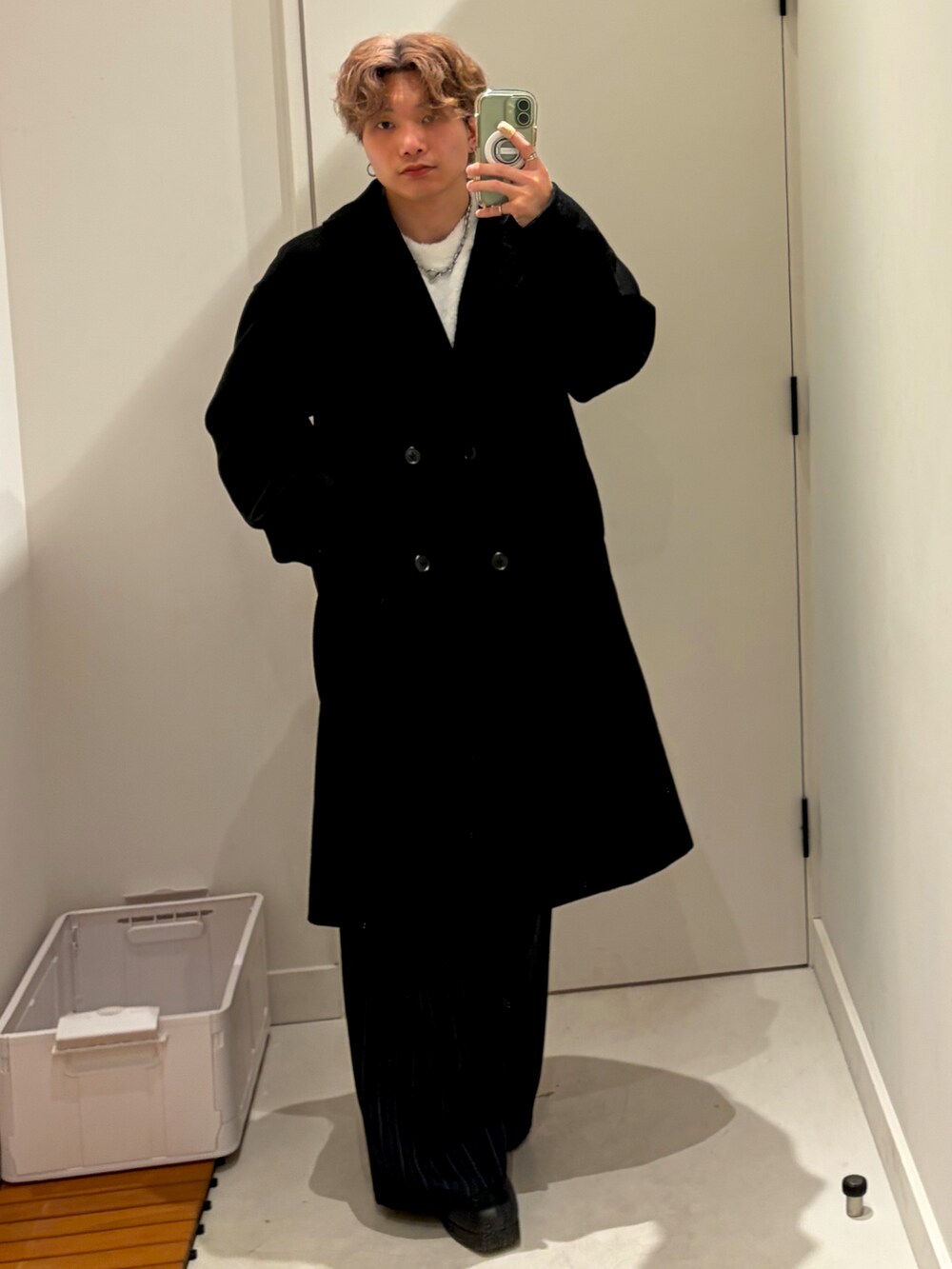 ホワイト系のスウェット、ブラック系のチェスターコート、ブルー系のパンツを着用したメンズの冬コーディネートの3枚目の写真