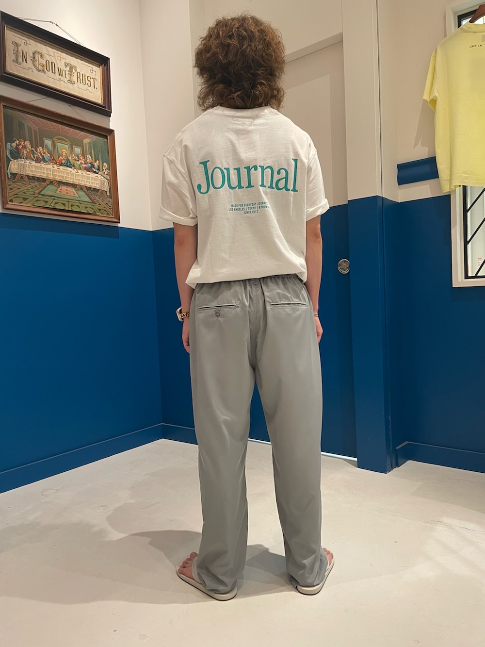 ホワイト系のサンダル、ホワイト系のTシャツ/カットソー、グレー系のパンツを着用したメンズの夏コーディネートの3枚目の写真