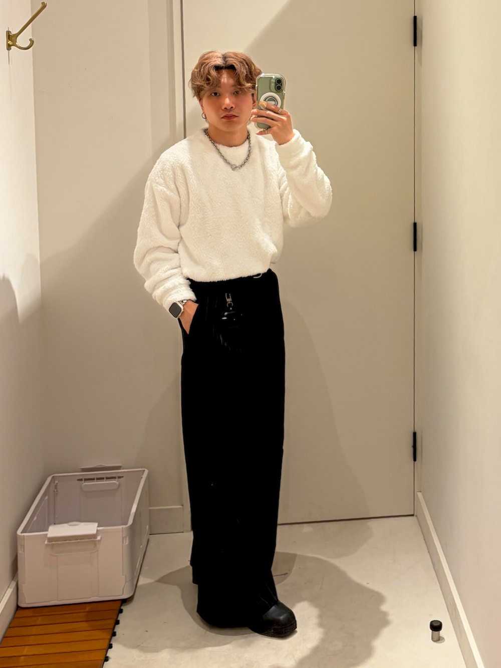 ホワイト系のスウェット、ブラック系のチェスターコート、ブルー系のパンツを着用したメンズの冬コーディネートの2枚目の写真