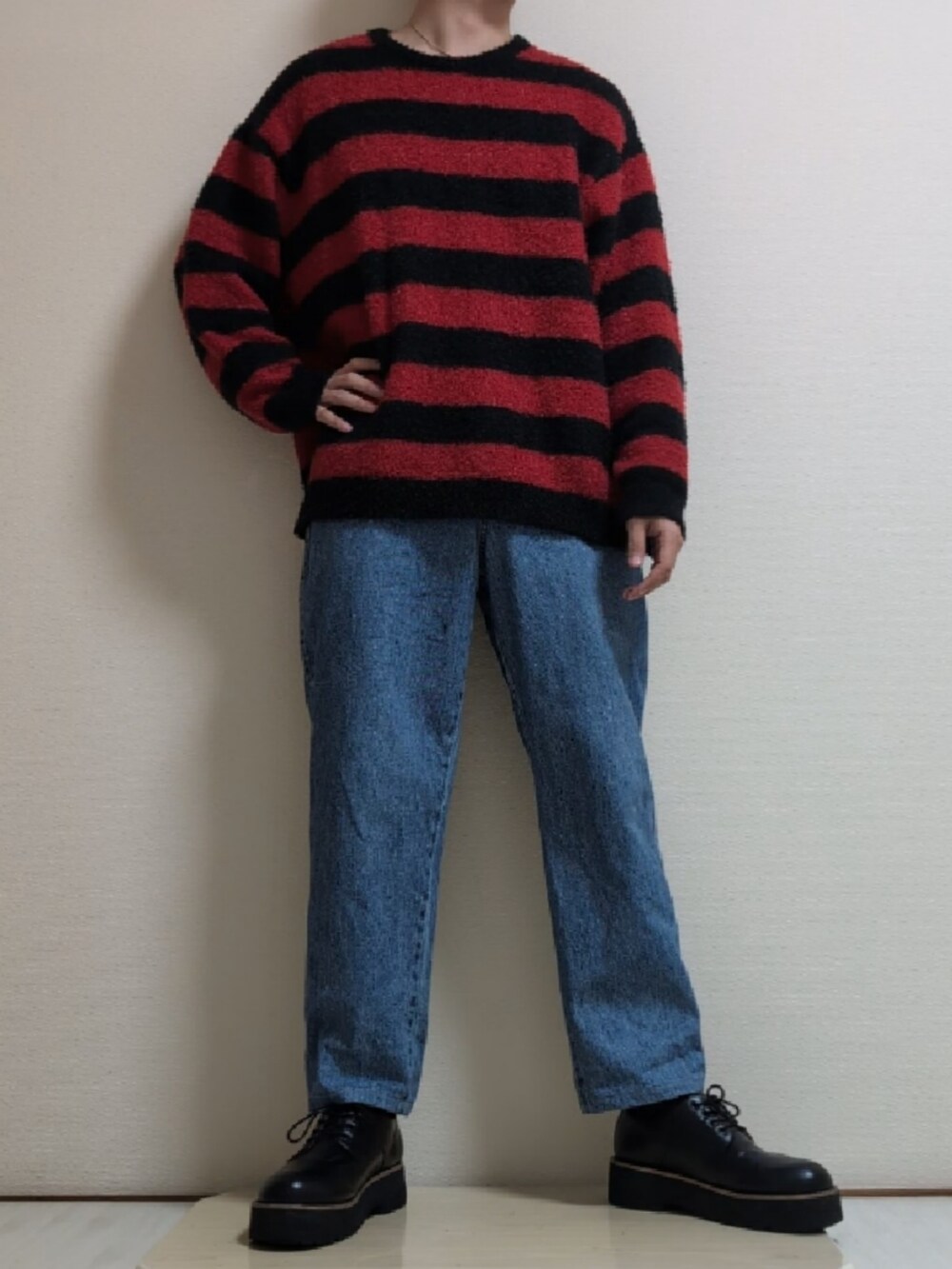 ブラック系のダウンジャケット/コート、レッド系のニット/セーター、ブルー系のデニムパンツを着用したメンズの冬コーディネートの2枚目の写真