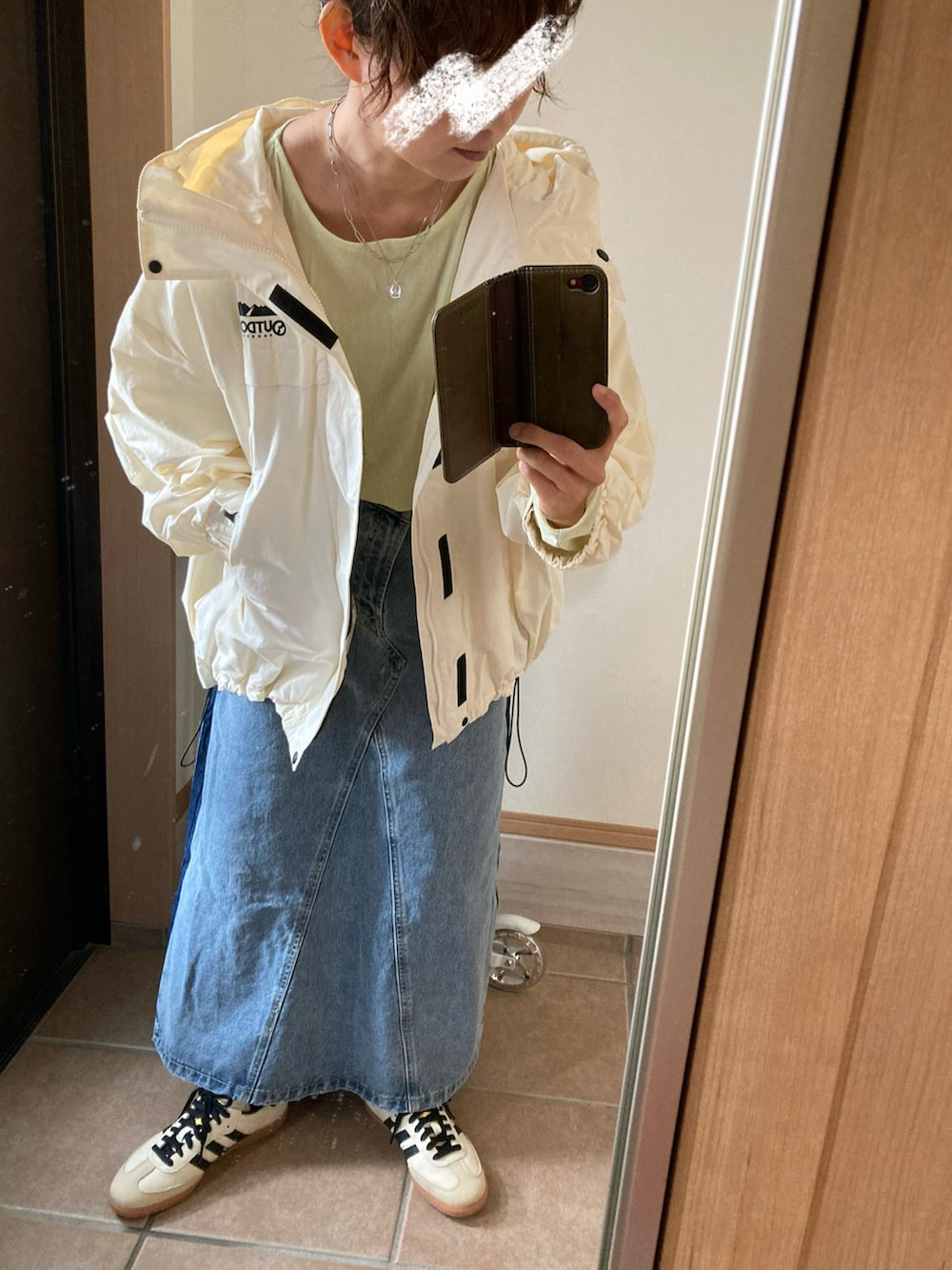 ホワイト系のマウンテンパーカー、グリーン系のTシャツ/カットソー、ブルー系のデニムスカートを着用したレディースの春コーディネートの2枚目の写真