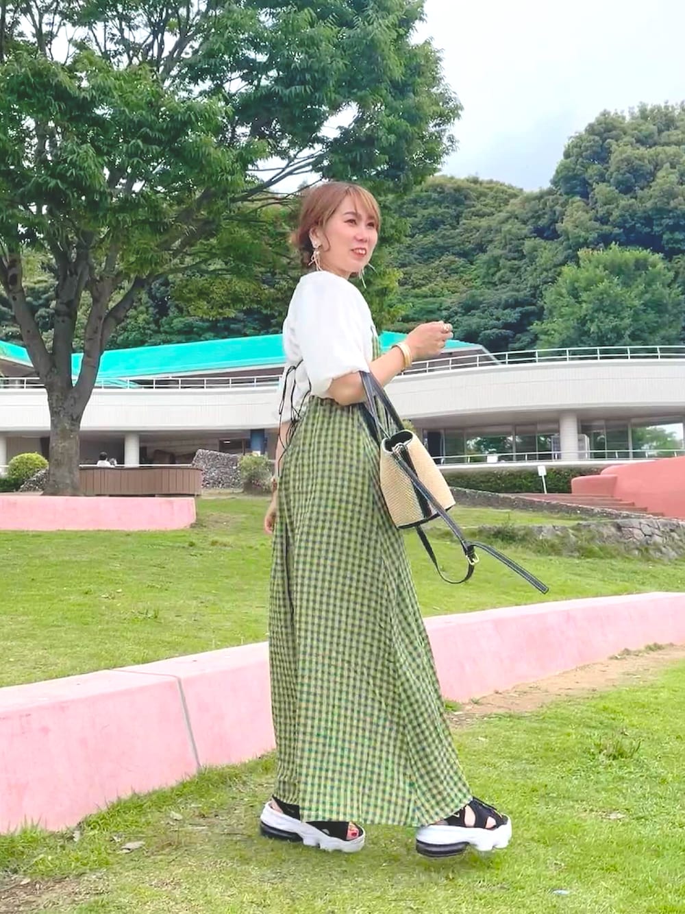 グリーン系のワンピース、ブラック系のサンダル、ブラウン系のバッグを着用したレディースの夏コーディネートの4枚目の写真