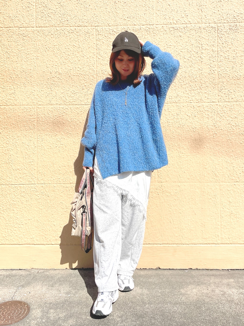 ブルー系のニット/セーター、ホワイト系のキャミソール、グレー系のスウェットパンツを着用したレディースの春コーディネートの2枚目の写真