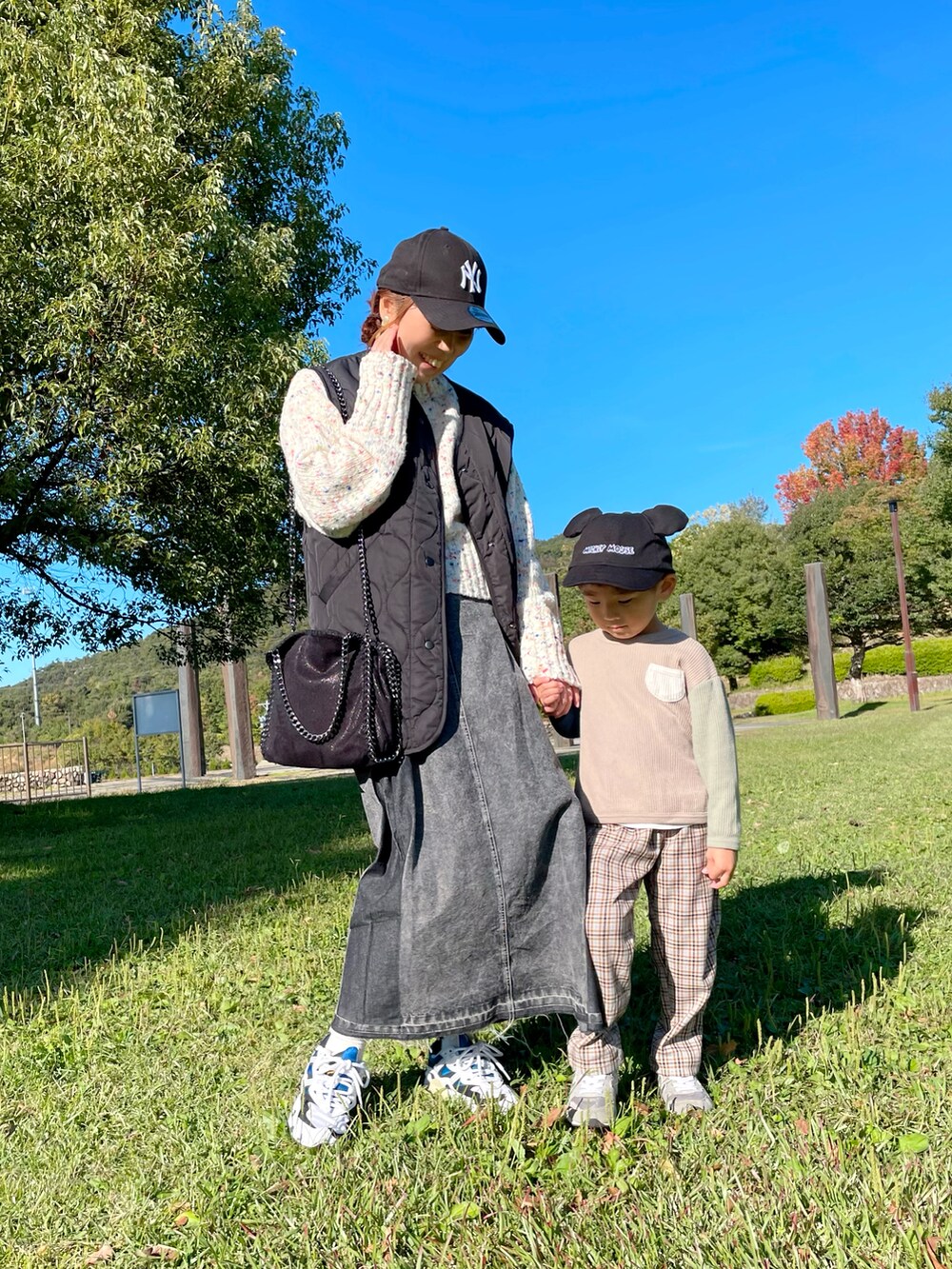 ホワイト系のニット/セーター、ブラック系のデニムスカート、ブラック系のハンドバッグを着用したレディースの秋コーディネートの5枚目の写真