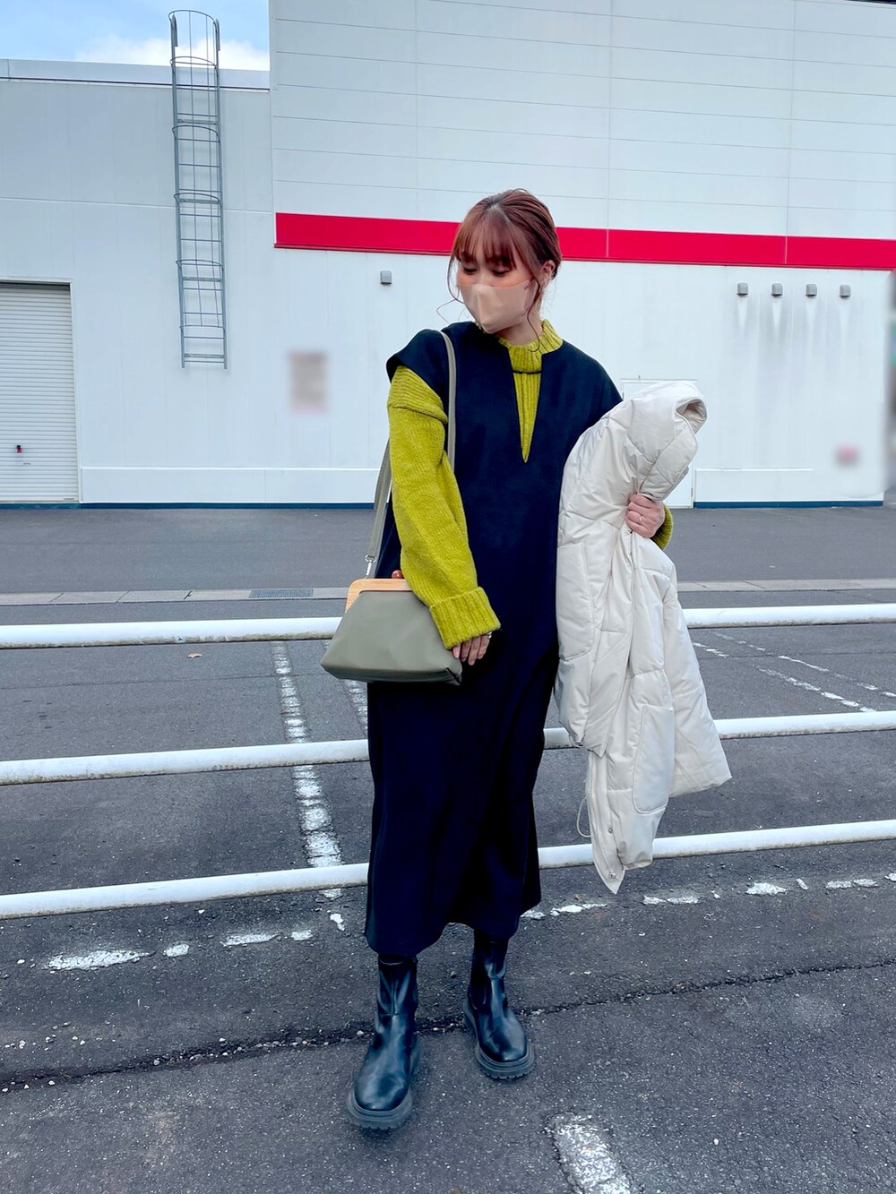 ホワイト系のジャケット/アウター、グリーン系のニット/セーター、ブラック系のワンピース/ドレスを着用したレディースの冬コーディネートの4枚目の写真