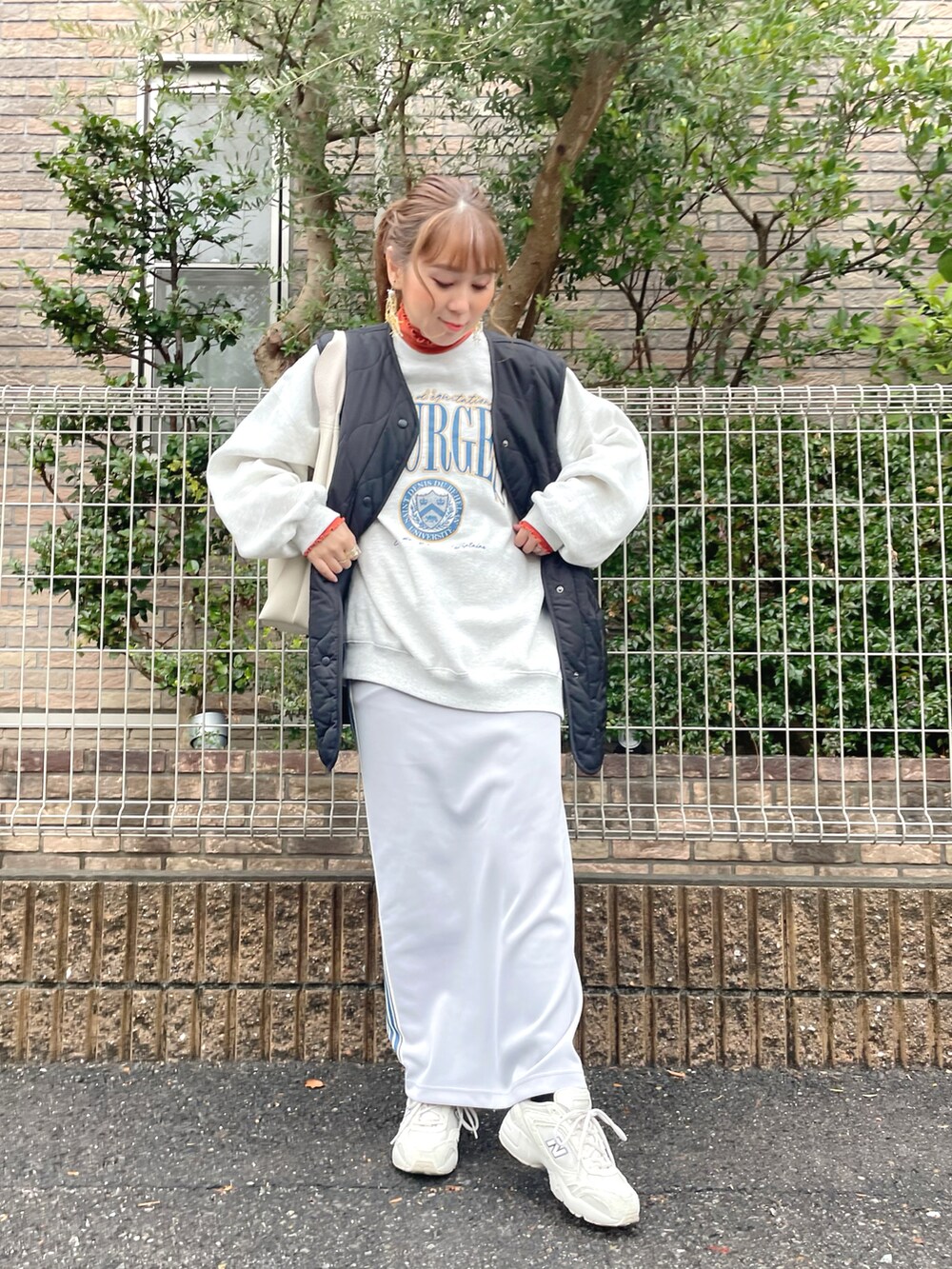 ベージュ系のスウェット、オレンジ系のトップス、グレー系のスカートを着用したレディースの冬コーディネートの3枚目の写真