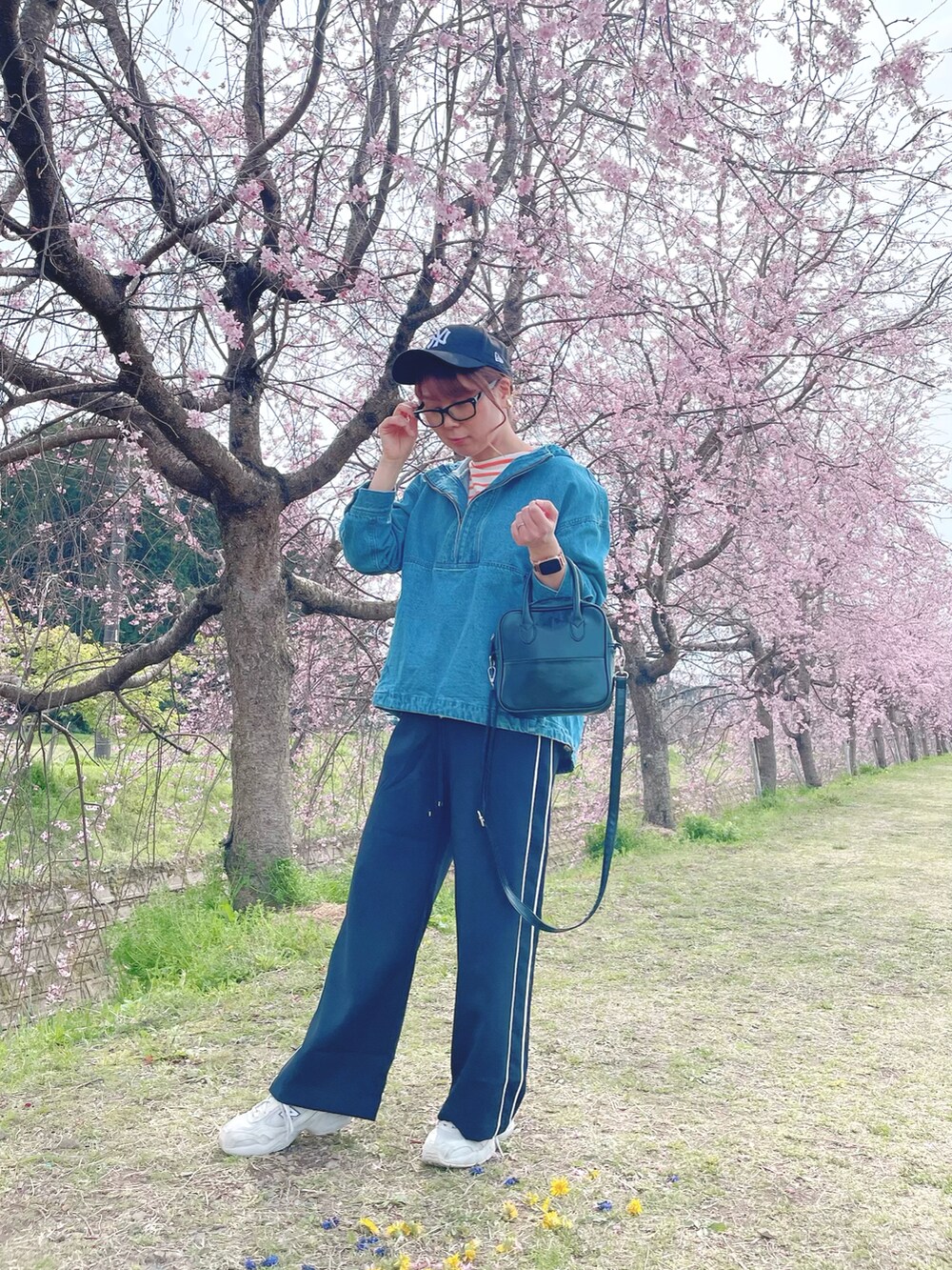 ブラック系のその他パンツ、ブルー系のトップス、オレンジ系のTシャツ/カットソーを着用したレディースの春コーディネートの2枚目の写真