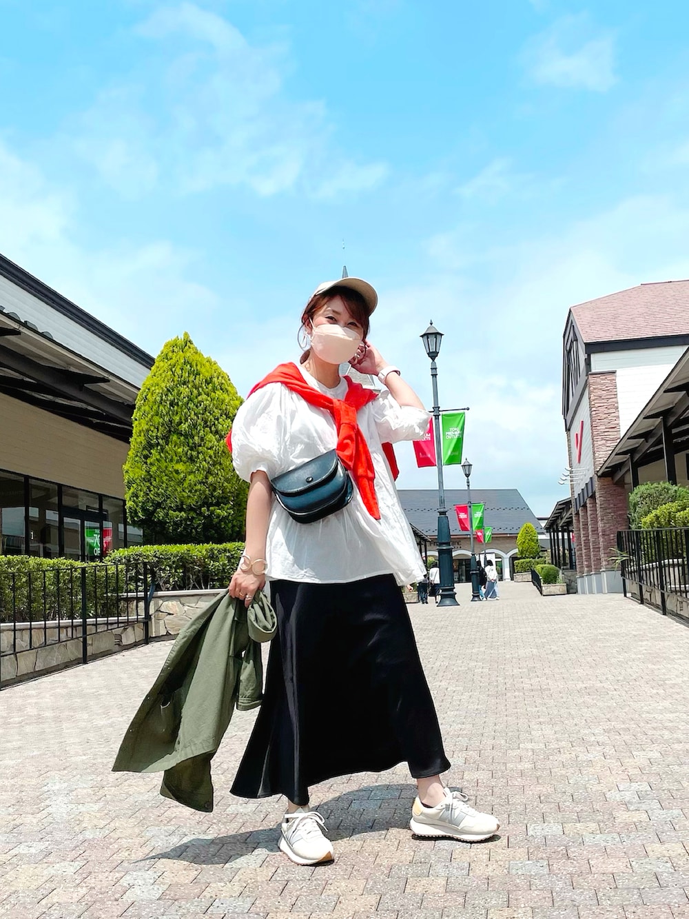 ホワイト系のスニーカー、オレンジ系のカーディガン/ボレロ、グリーン系のミリタリージャケットを着用したレディースの春コーディネートの2枚目の写真