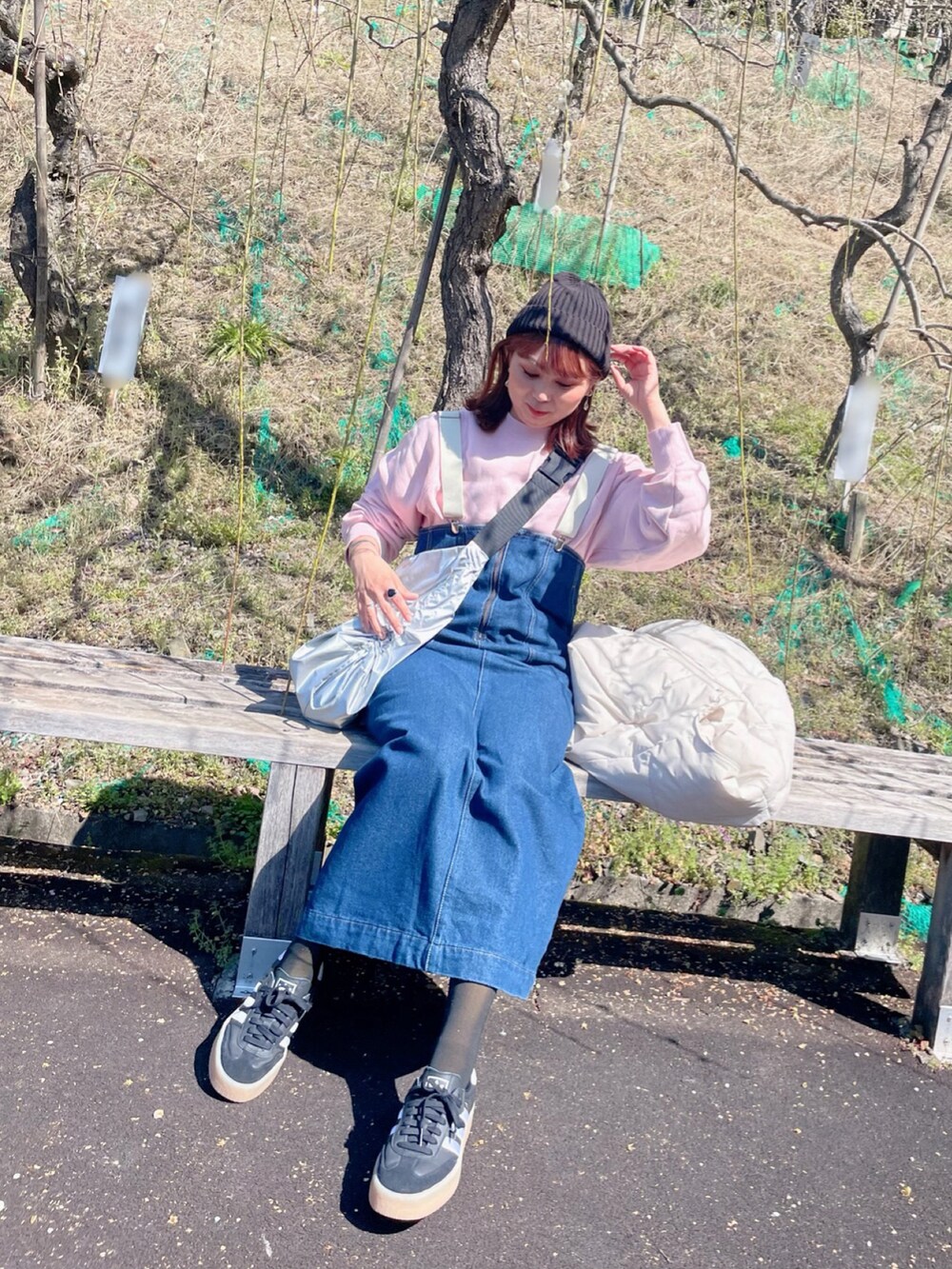 ピンク系のスウェット、ブルー系のオールインワン・サロペット、ブラック系のスニーカーを着用したレディースの春コーディネートの2枚目の写真