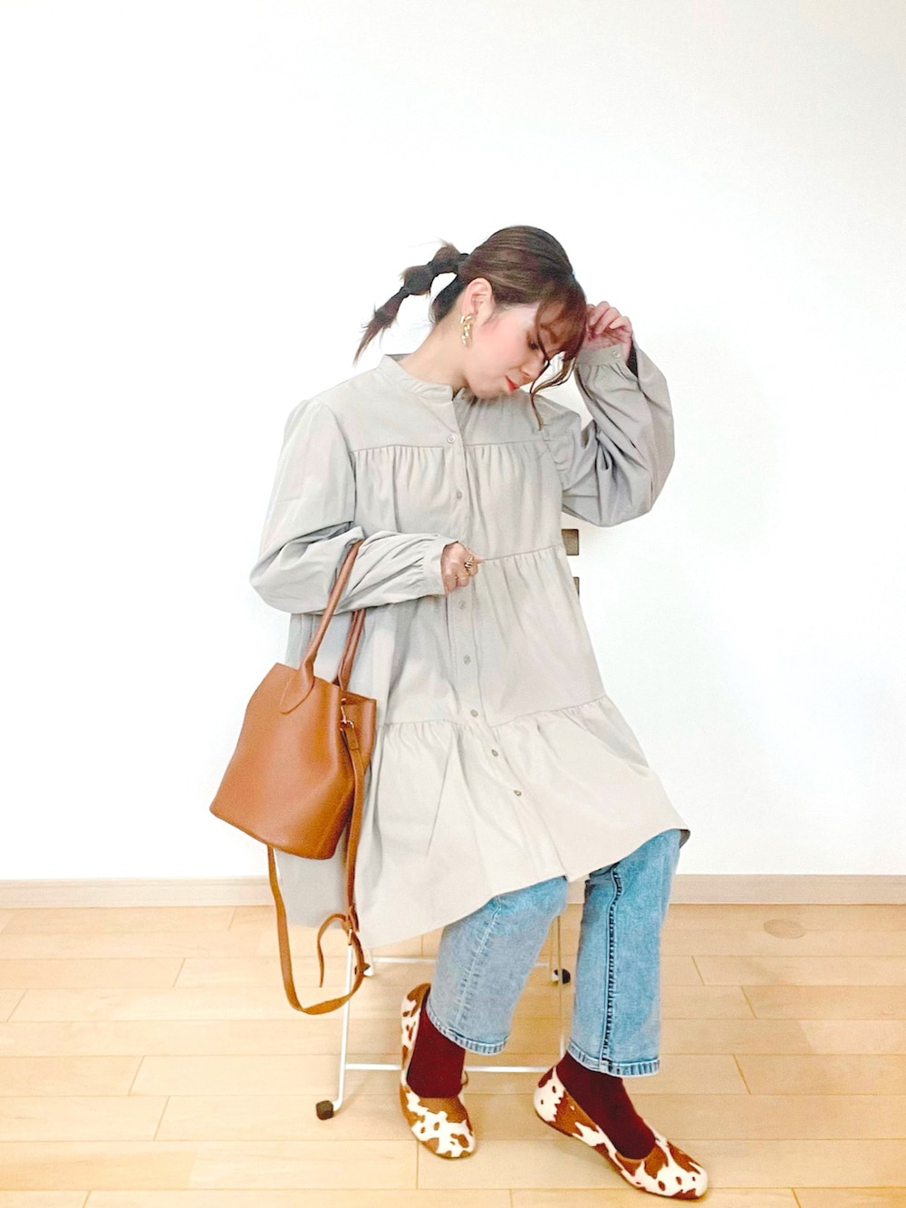 ブルー系のデニムパンツ、ベージュ系のワンピース、ブラウン系のバッグを着用したレディースの秋コーディネートの2枚目の写真