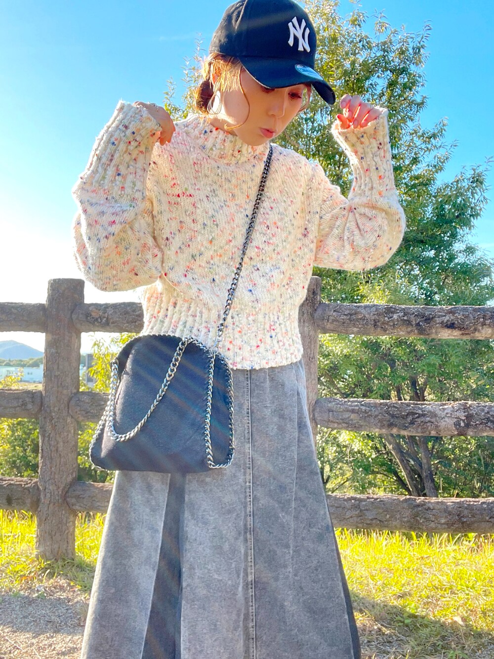 ホワイト系のニット/セーター、ブラック系のデニムスカート、ブラック系のハンドバッグを着用したレディースの秋コーディネートの4枚目の写真