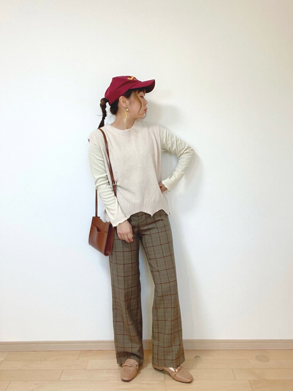 ホワイト系のベスト、ブラウン系のパンツ、ベージュ系のローファーを着用したレディースの冬コーディネートの2枚目の写真