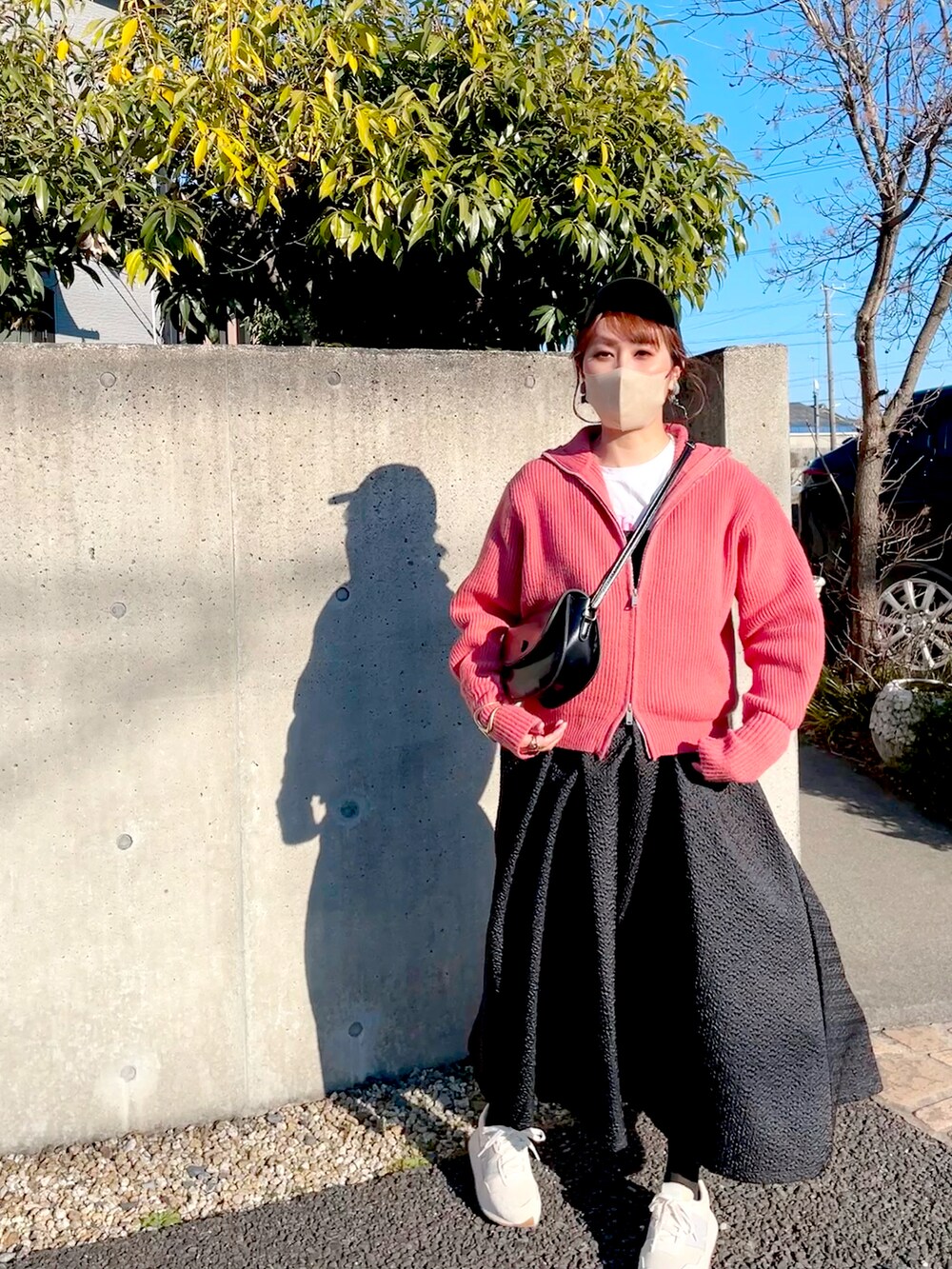ブラック系のワンピース、ピンク系のニット/セーター、ホワイト系のTシャツ/カットソーを着用したレディースの春コーディネートの2枚目の写真