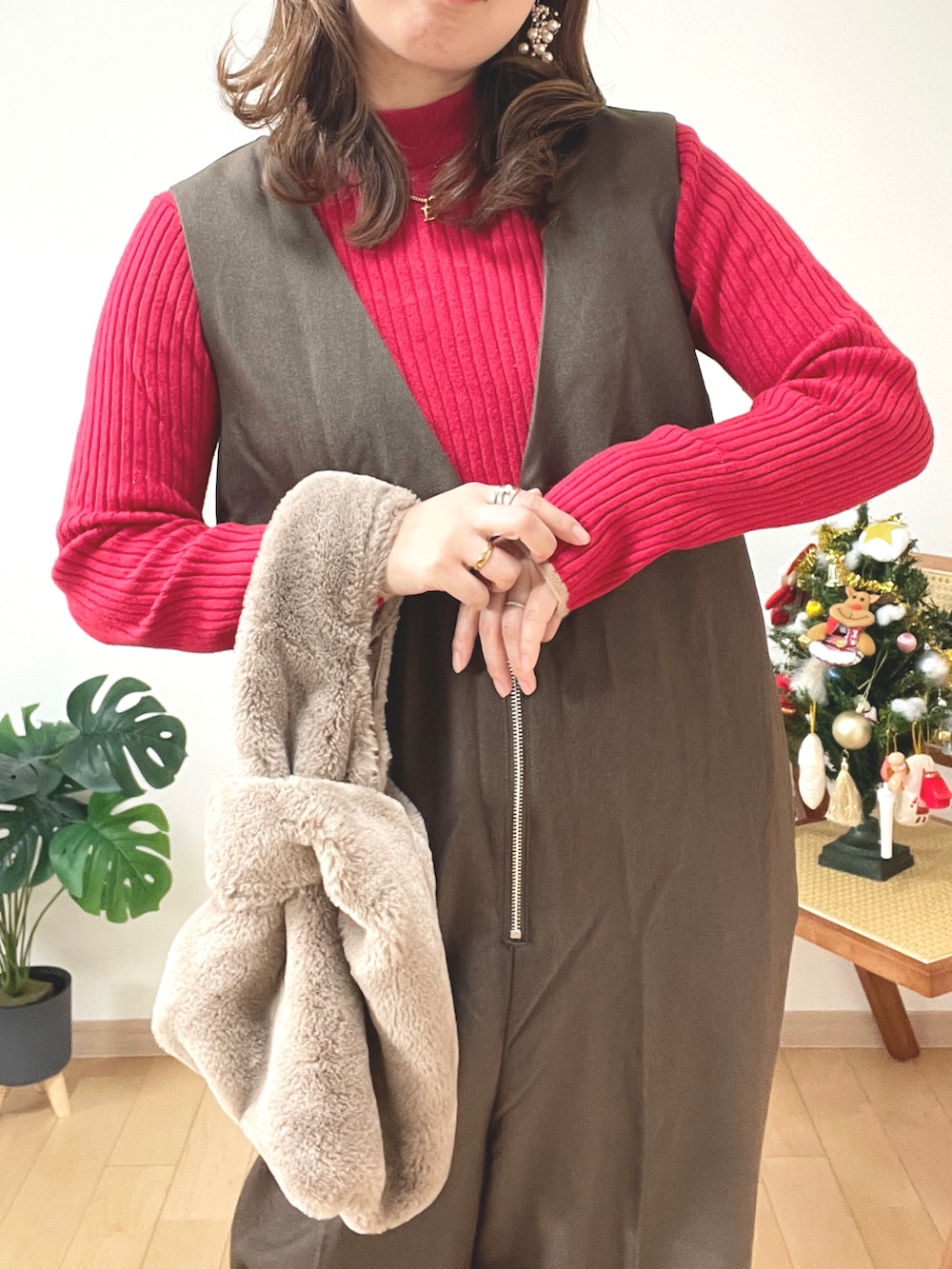 レッド系のニット/セーター、ブラウン系のつなぎ/オールインワン、ブラック系のブーツを着用したレディースの冬コーディネートの3枚目の写真