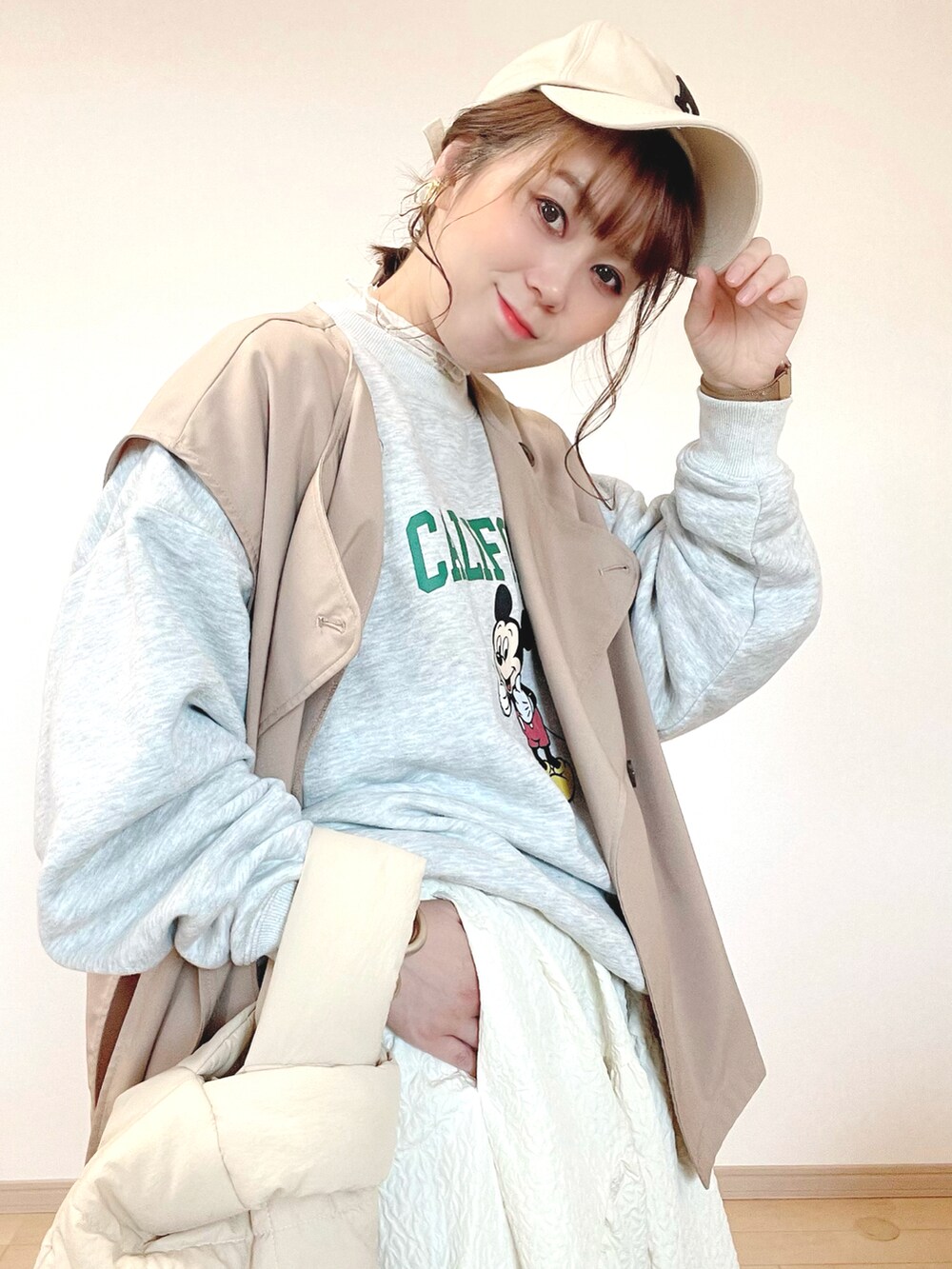 グレー系のスウェット、ベージュ系のベスト、ホワイト系のスカートを着用したレディースの春コーディネートの4枚目の写真