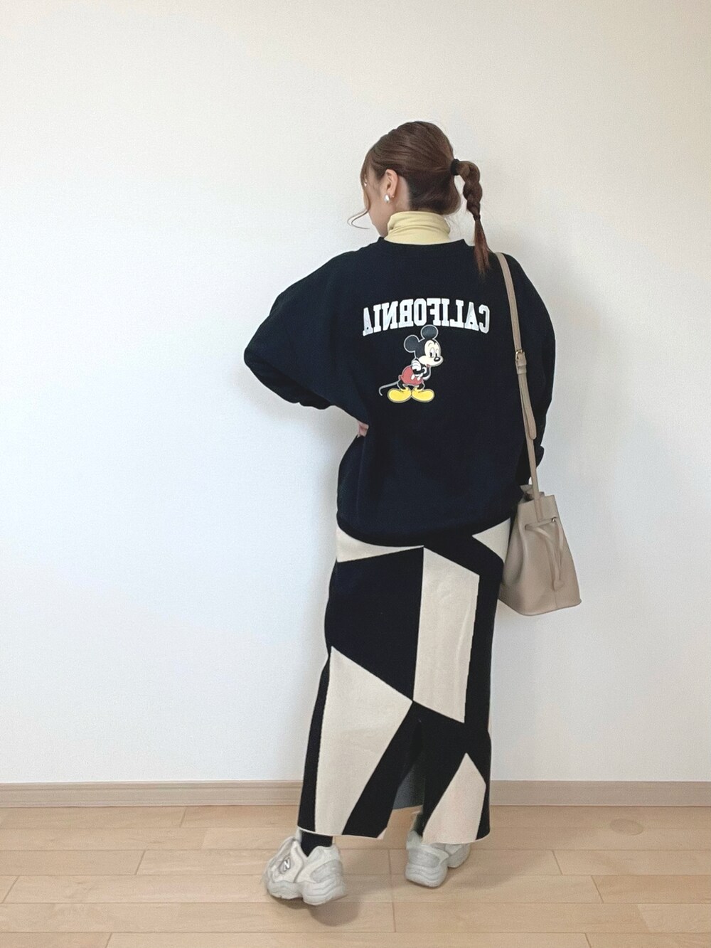 ブラック系のスウェット、イエロー系のトップス、ブラック系のスカートを着用したレディースの冬コーディネートの4枚目の写真