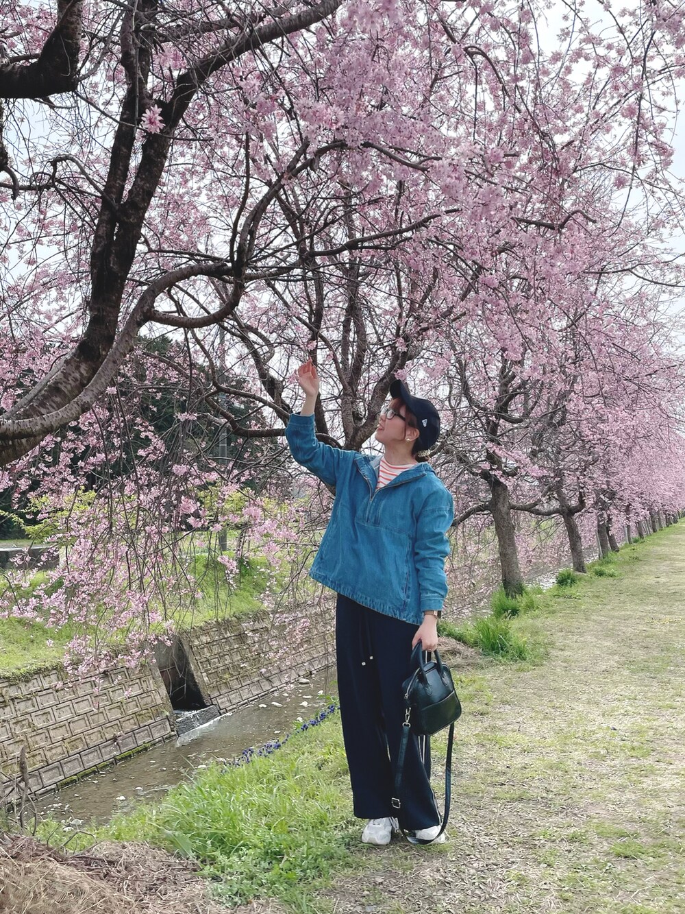 ブラック系のその他パンツ、ブルー系のトップス、オレンジ系のTシャツ/カットソーを着用したレディースの春コーディネートの4枚目の写真