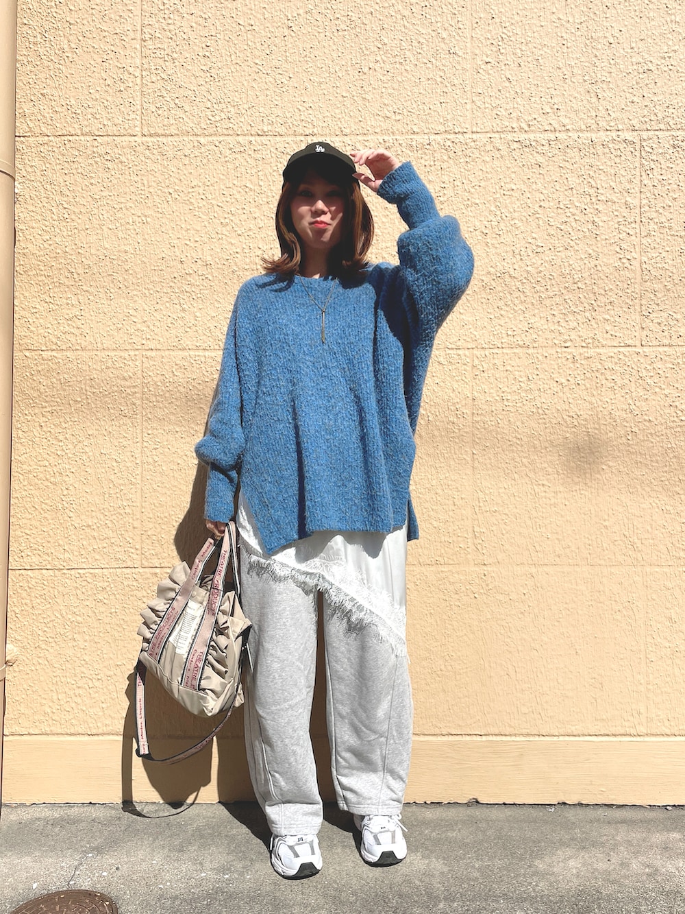 ブルー系のニット/セーター、ホワイト系のキャミソール、グレー系のスウェットパンツを着用したレディースの春コーディネートの3枚目の写真