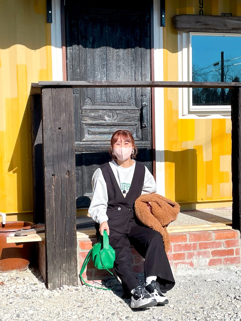 グレー系のスウェット、ブラック系のオールインワン・サロペット、グリーン系のその他アウターを着用したレディースの冬コーディネートの3枚目の写真