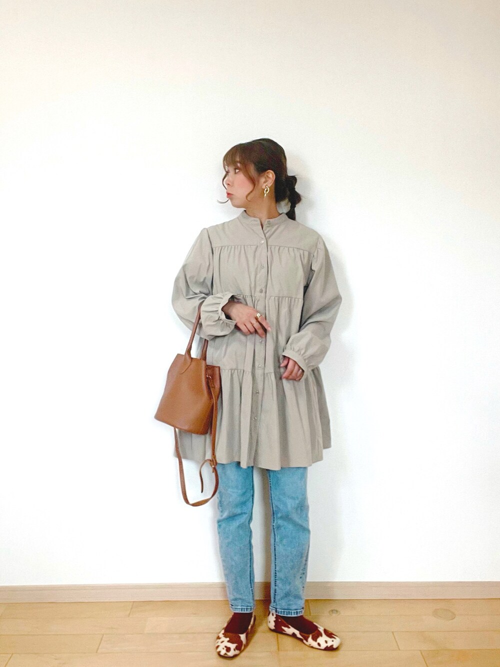 ブルー系のデニムパンツ、ベージュ系のワンピース、ブラウン系のバッグを着用したレディースの秋コーディネートの3枚目の写真