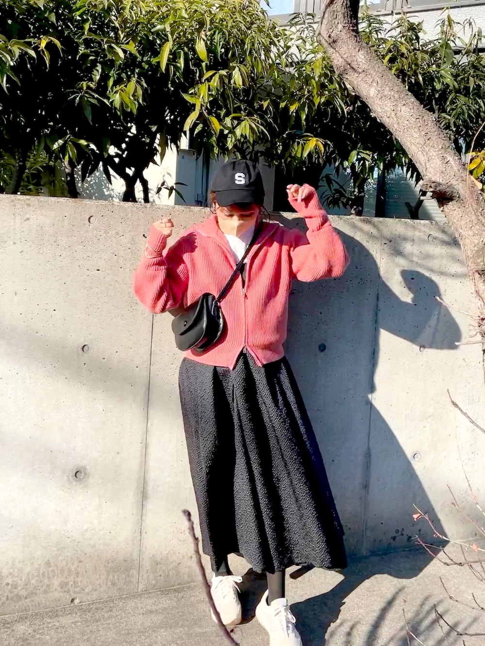 ブラック系のワンピース、ピンク系のニット/セーター、ホワイト系のTシャツ/カットソーを着用したレディースの春コーディネートの3枚目の写真