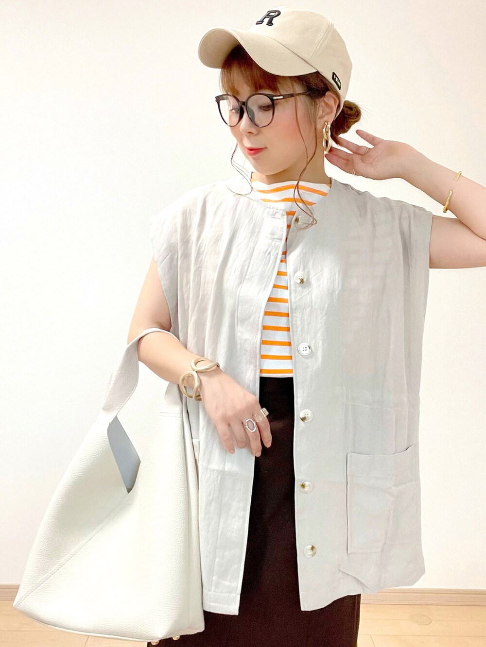 グレー系のベスト、オレンジ系のTシャツ/カットソー、ブラウン系のスカートを着用したレディースの夏コーディネートの4枚目の写真