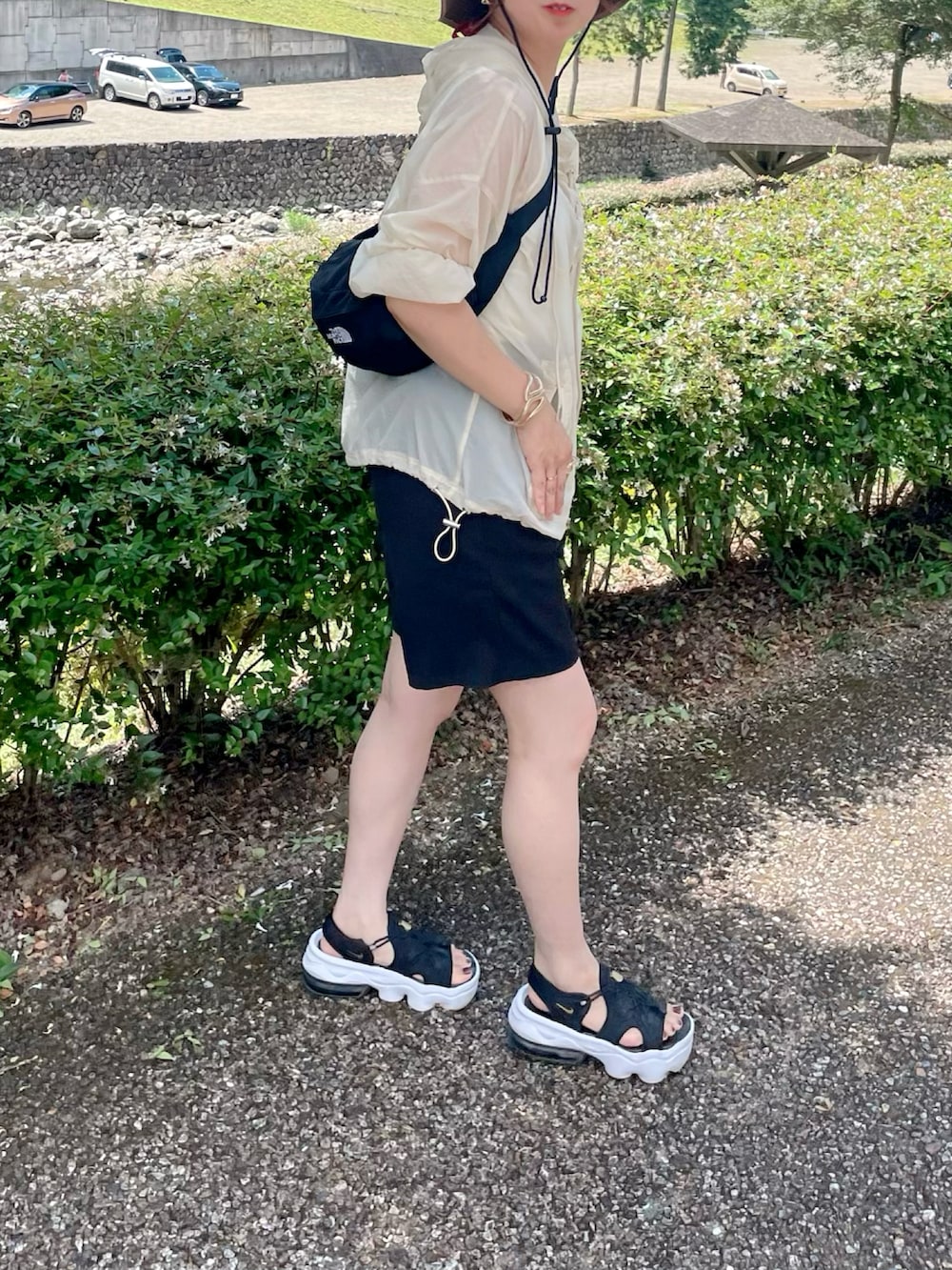 ベージュ系のトップス、ブラック系のパンツ、ブラック系のサンダルを着用したレディースの夏コーディネートの4枚目の写真