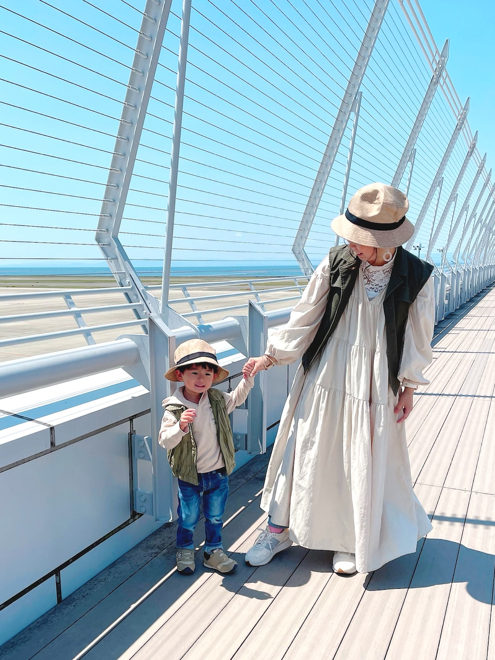 グリーン系のベスト、ホワイト系のタンクトップ、ホワイト系のワンピースを着用したレディースの春コーディネートの2枚目の写真