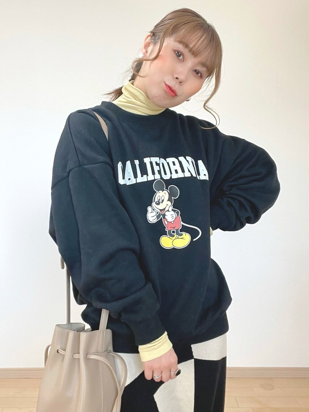 ブラック系のスウェット、イエロー系のトップス、ブラック系のスカートを着用したレディースの冬コーディネートの5枚目の写真