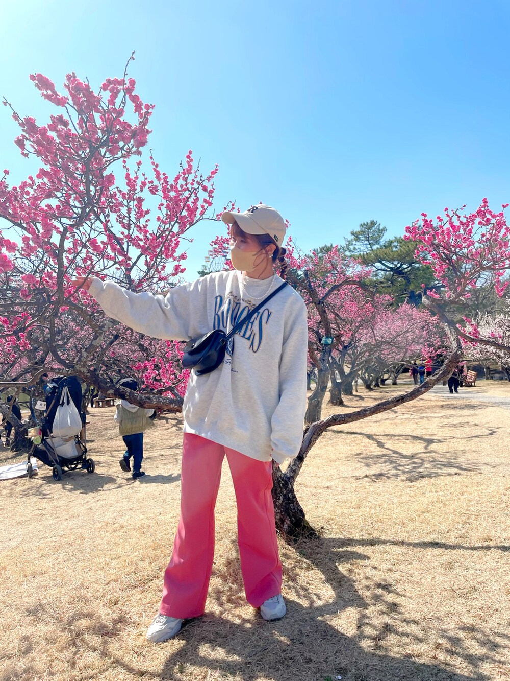 ベージュ系のスウェット、ホワイト系のジャケット/アウター、ピンク系のスラックスを着用したレディースの春コーディネートの3枚目の写真