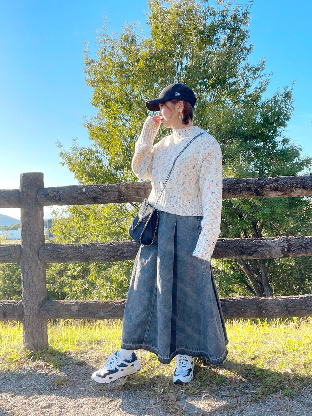 ホワイト系のニット/セーター、ブラック系のデニムスカート、ブラック系のハンドバッグを着用したレディースの秋コーディネートの3枚目の写真