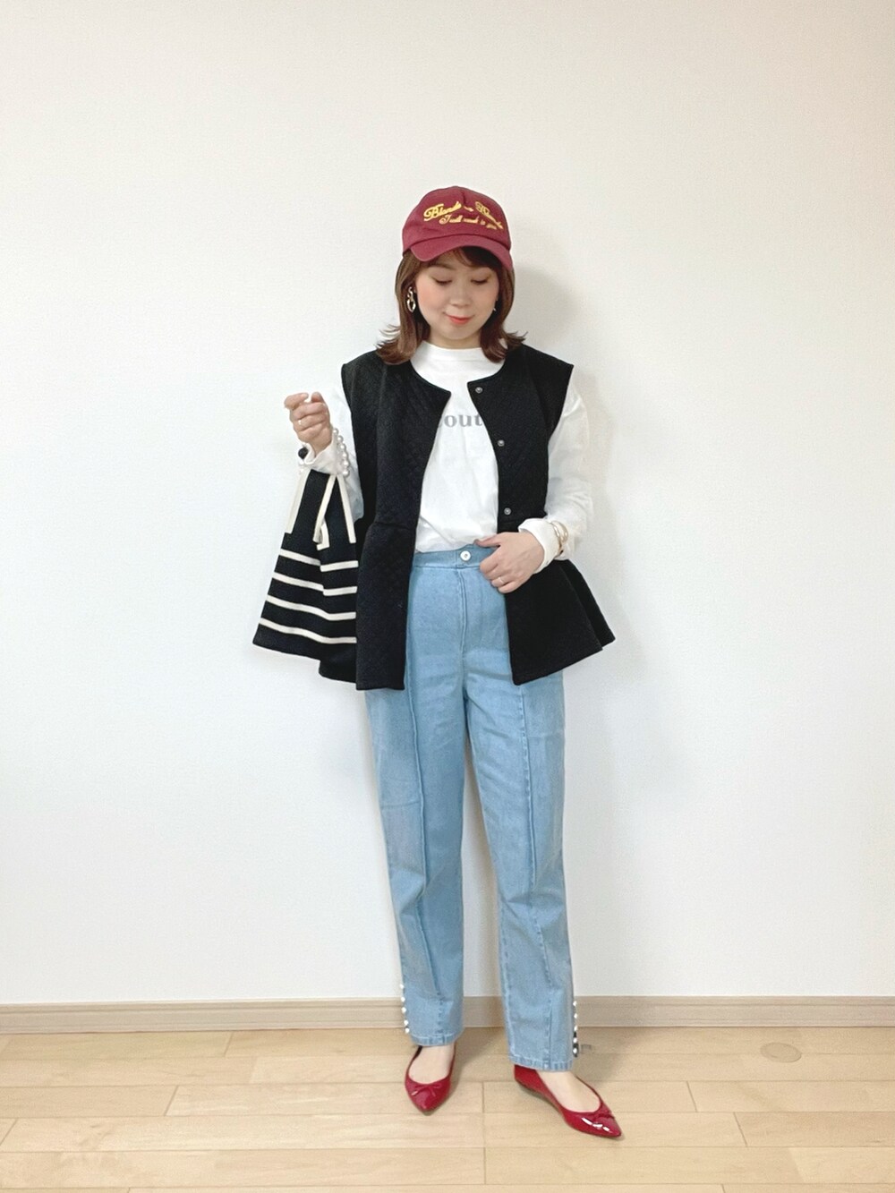 ブラック系のベスト、ブルー系のデニムパンツ、ホワイト系のTシャツ/カットソーを着用したレディースの春コーディネートの2枚目の写真