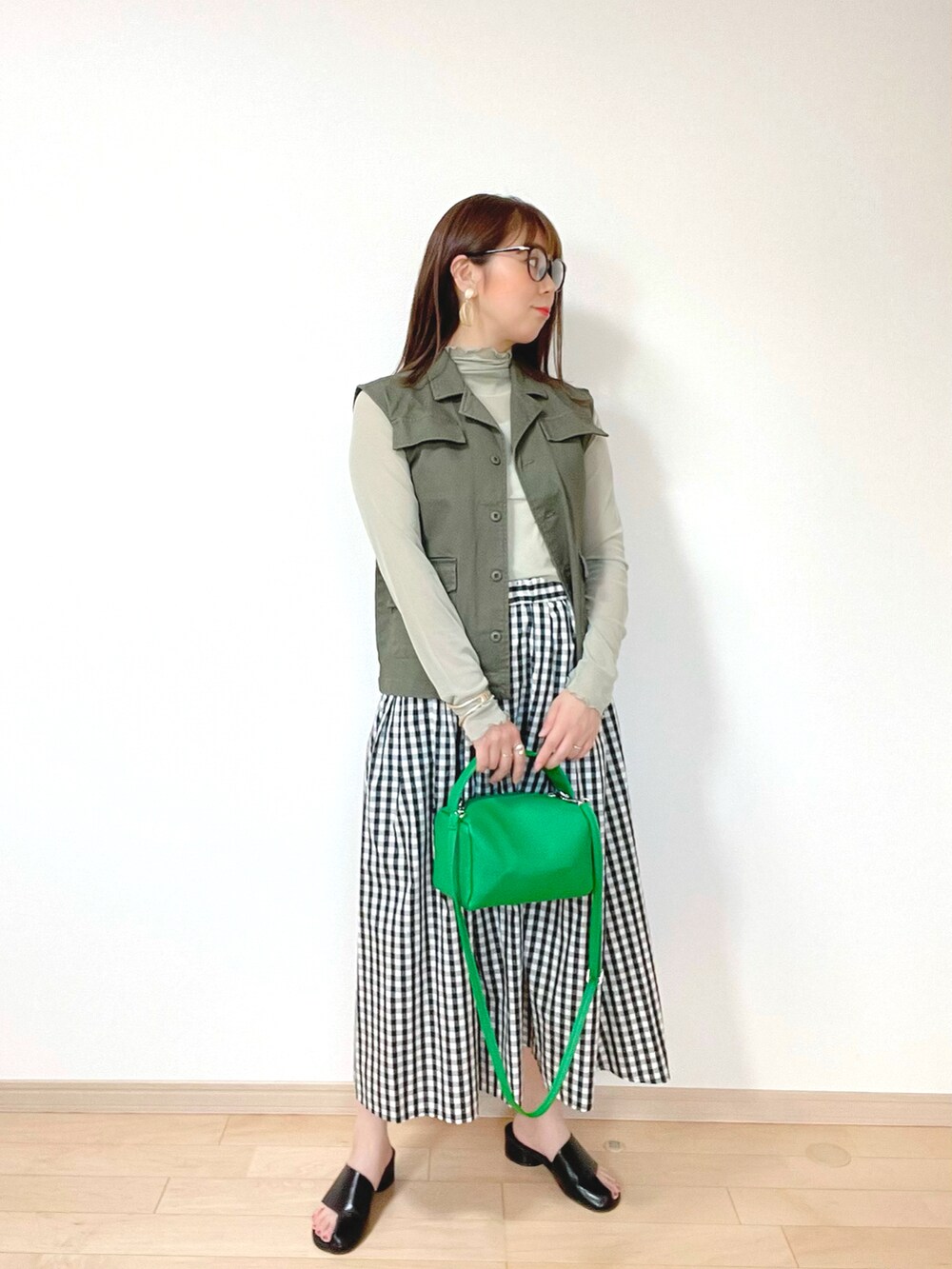 グリーン系のベスト、グリーン系のトップス、ブラック系のスカートを着用したレディースの夏コーディネートの2枚目の写真