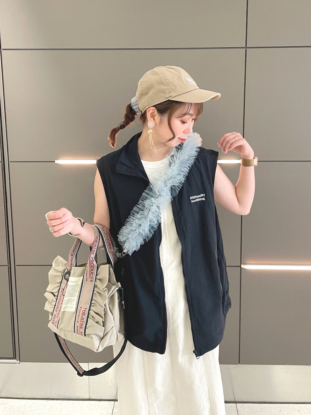 ブラック系のベスト、ホワイト系のタンクトップ、ベージュ系のジャンパースカートを着用したレディースの夏コーディネートの5枚目の写真