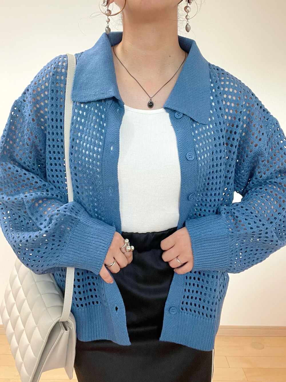 ホワイト系のタンクトップ、ブルー系のカーディガン/ボレロ、ブラック系のスカートを着用したレディースの秋コーディネートの5枚目の写真