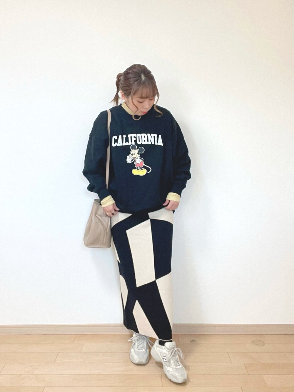 ブラック系のスウェット、イエロー系のトップス、ブラック系のスカートを着用したレディースの冬コーディネートの3枚目の写真