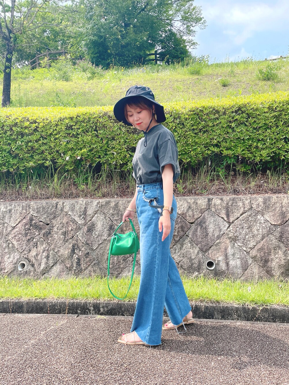 グレー系のTシャツ/カットソー、ブルー系のデニムパンツ、ゴールド系のサンダルを着用したレディースの夏コーディネートの4枚目の写真