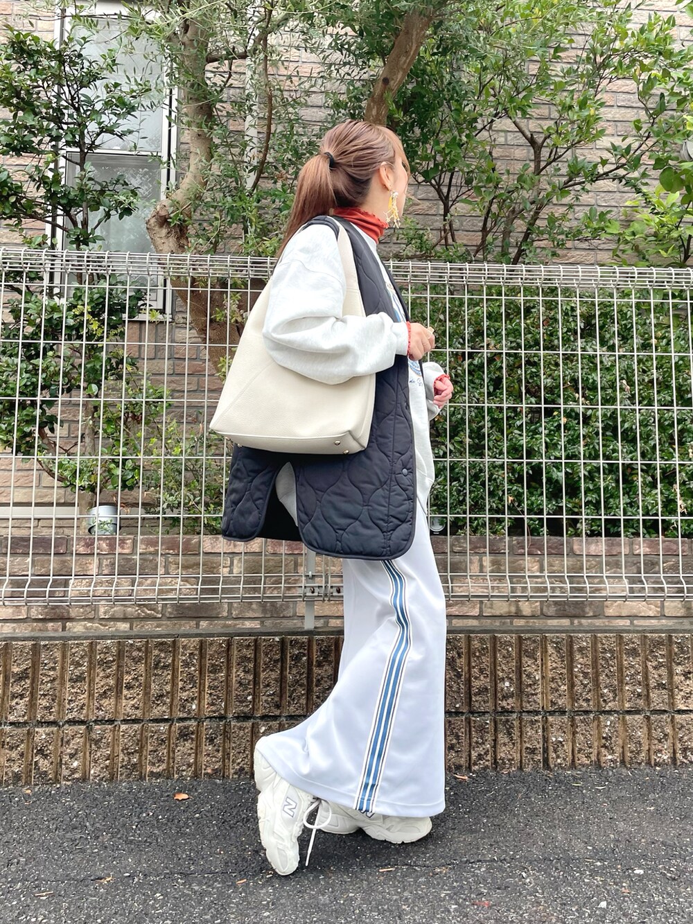 ベージュ系のスウェット、オレンジ系のトップス、グレー系のスカートを着用したレディースの冬コーディネートの4枚目の写真