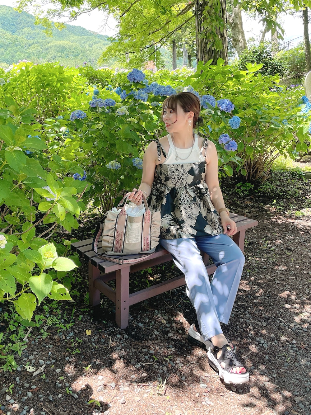 ブラック系のキャミソール、ホワイト系のタンクトップ、ベージュ系のショルダーバッグを着用したレディースの夏コーディネートの2枚目の写真