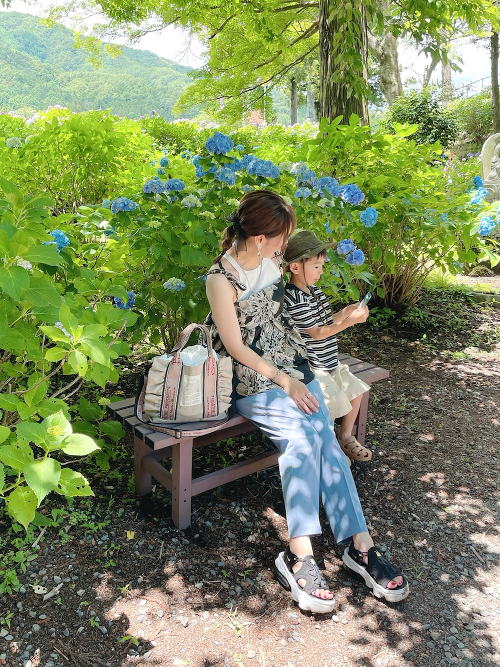 ブラック系のキャミソール、ホワイト系のタンクトップ、ベージュ系のショルダーバッグを着用したレディースの夏コーディネートの4枚目の写真