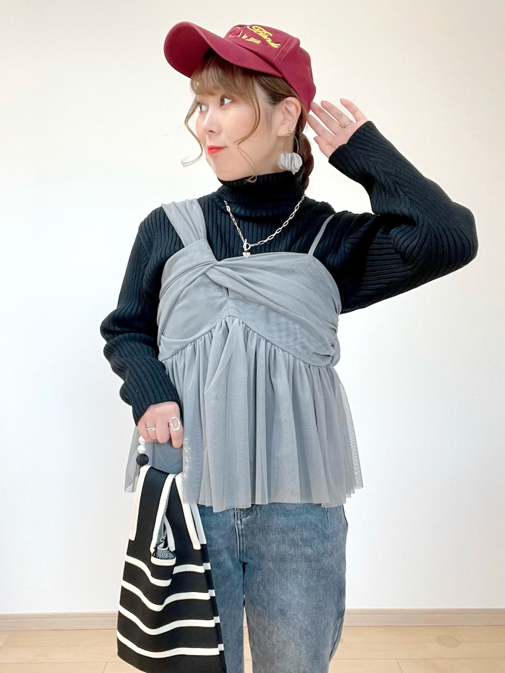 グレー系のキャミソール、ホワイト系のニット/セーター、グレー系のデニムパンツを着用したレディースの冬コーディネートの4枚目の写真