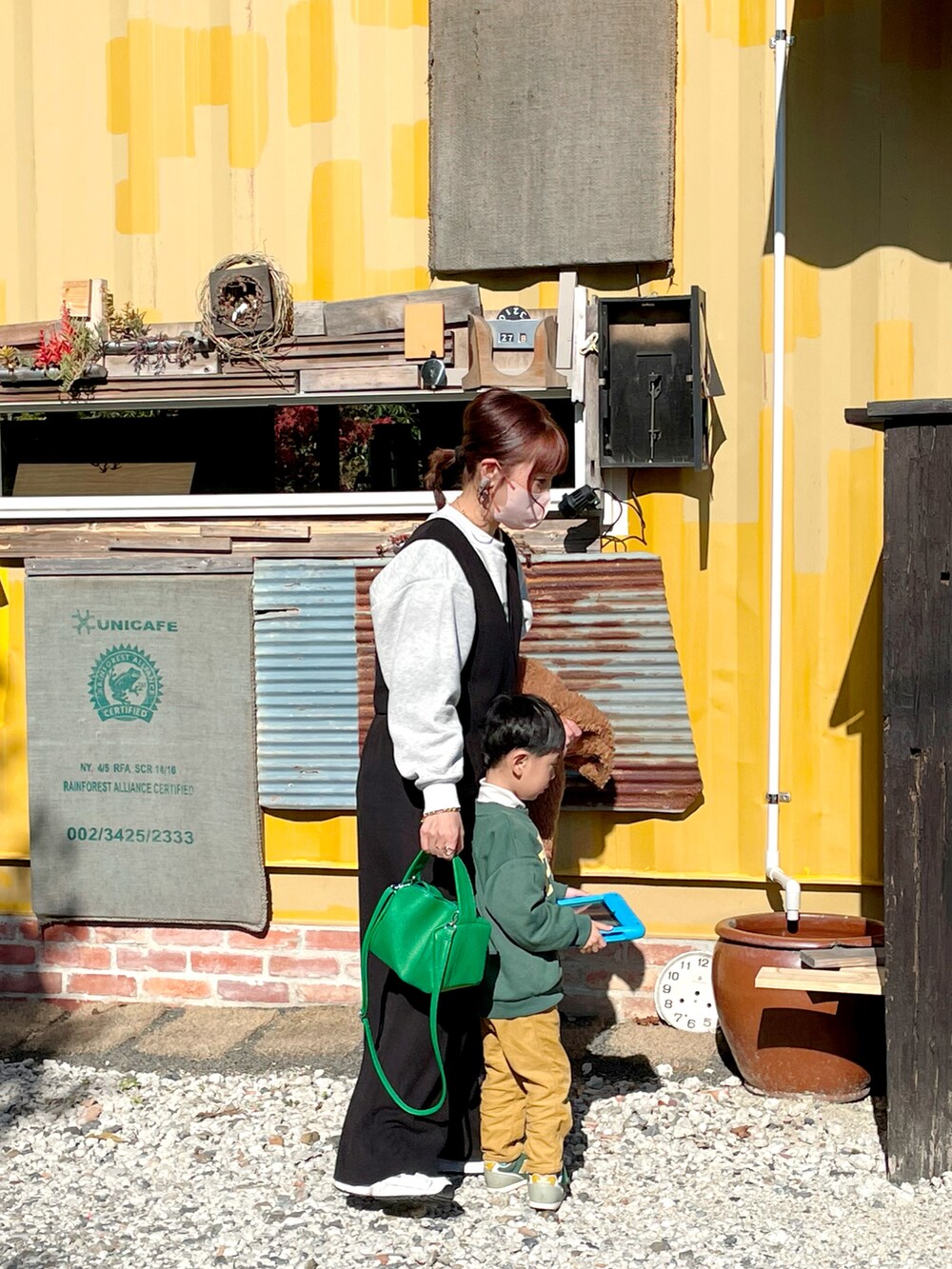 グレー系のスウェット、ブラック系のオールインワン・サロペット、グリーン系のその他アウターを着用したレディースの冬コーディネートの2枚目の写真