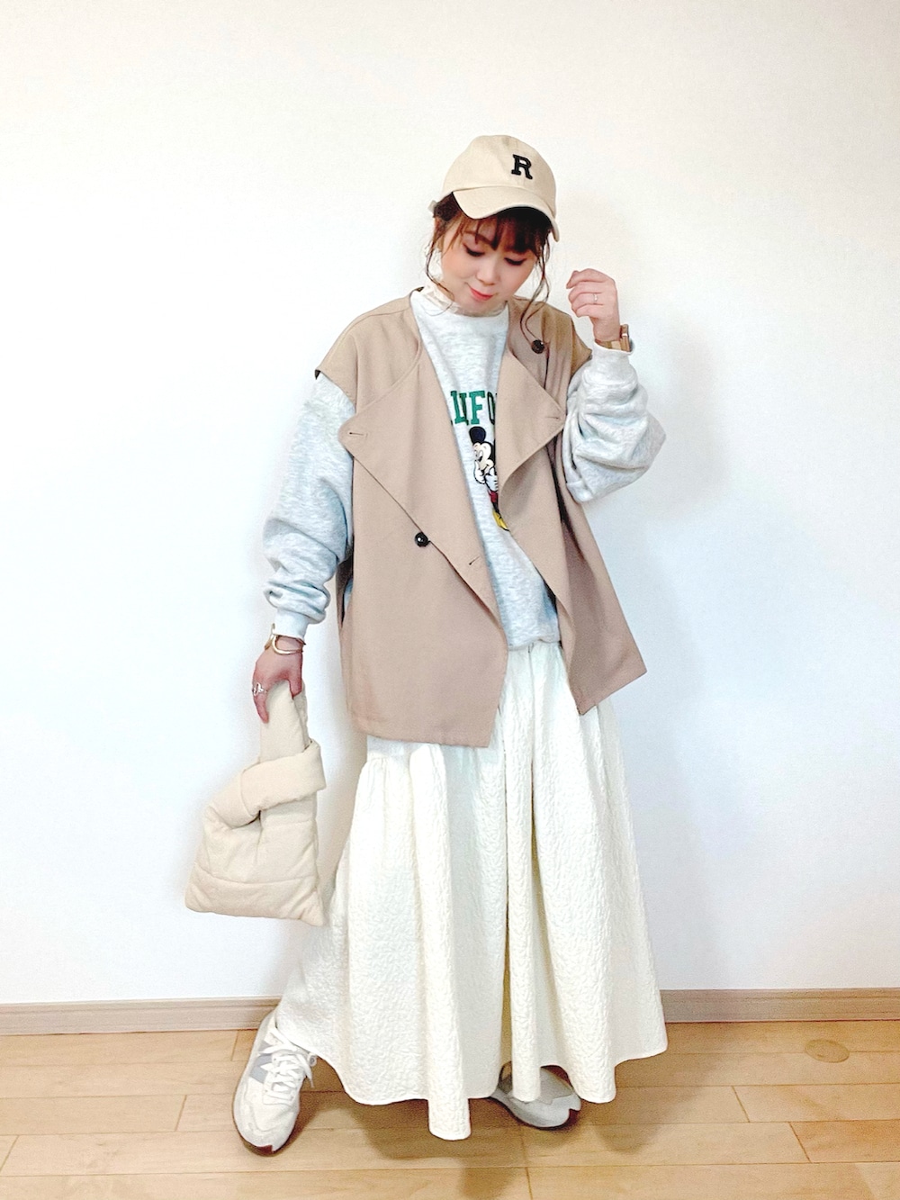 グレー系のスウェット、ベージュ系のベスト、ホワイト系のスカートを着用したレディースの春コーディネートの3枚目の写真