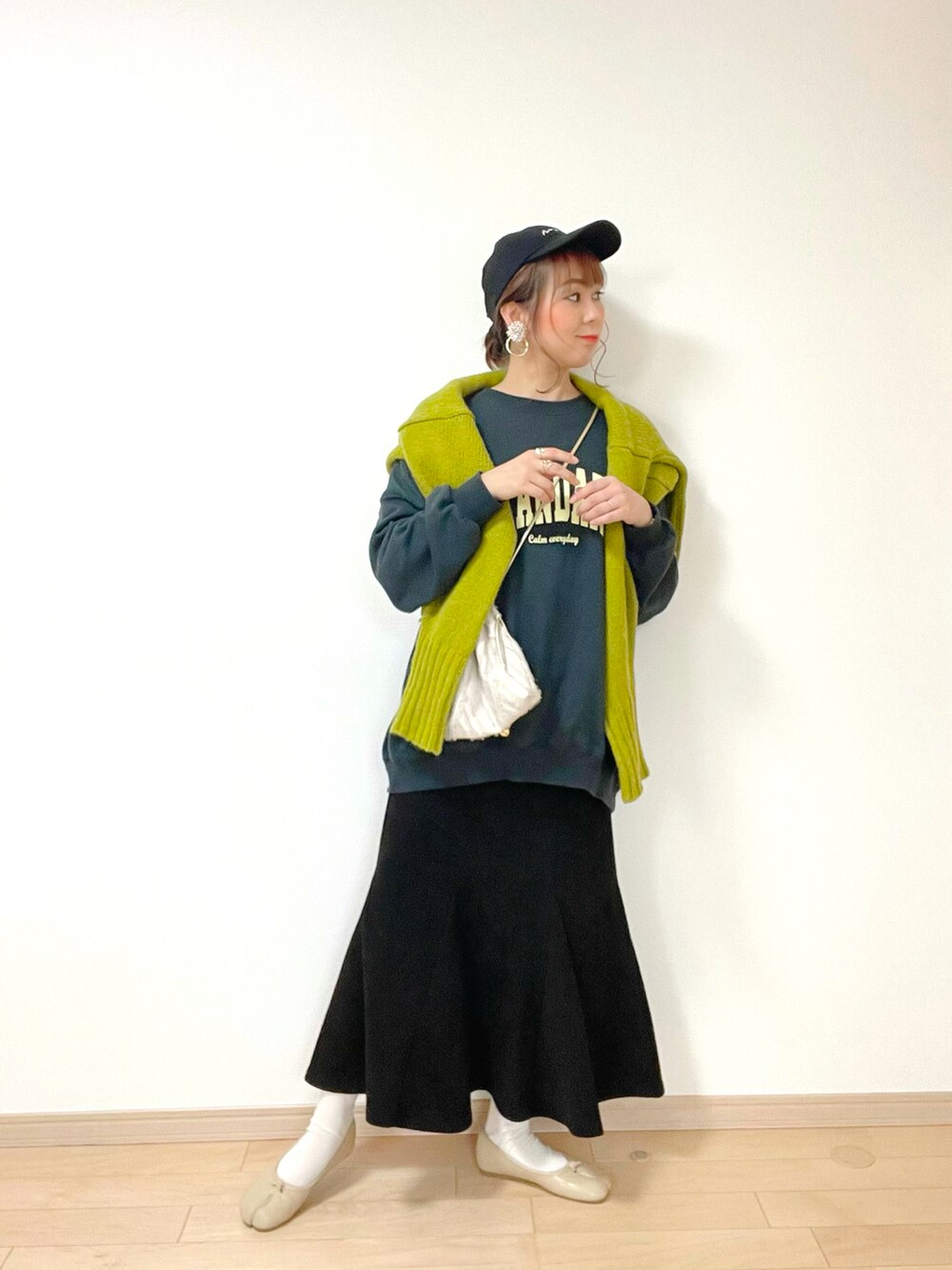 ブラック系のスウェット、グリーン系のニット/セーター、ブラック系のスカートを着用したレディースの冬コーディネートの2枚目の写真