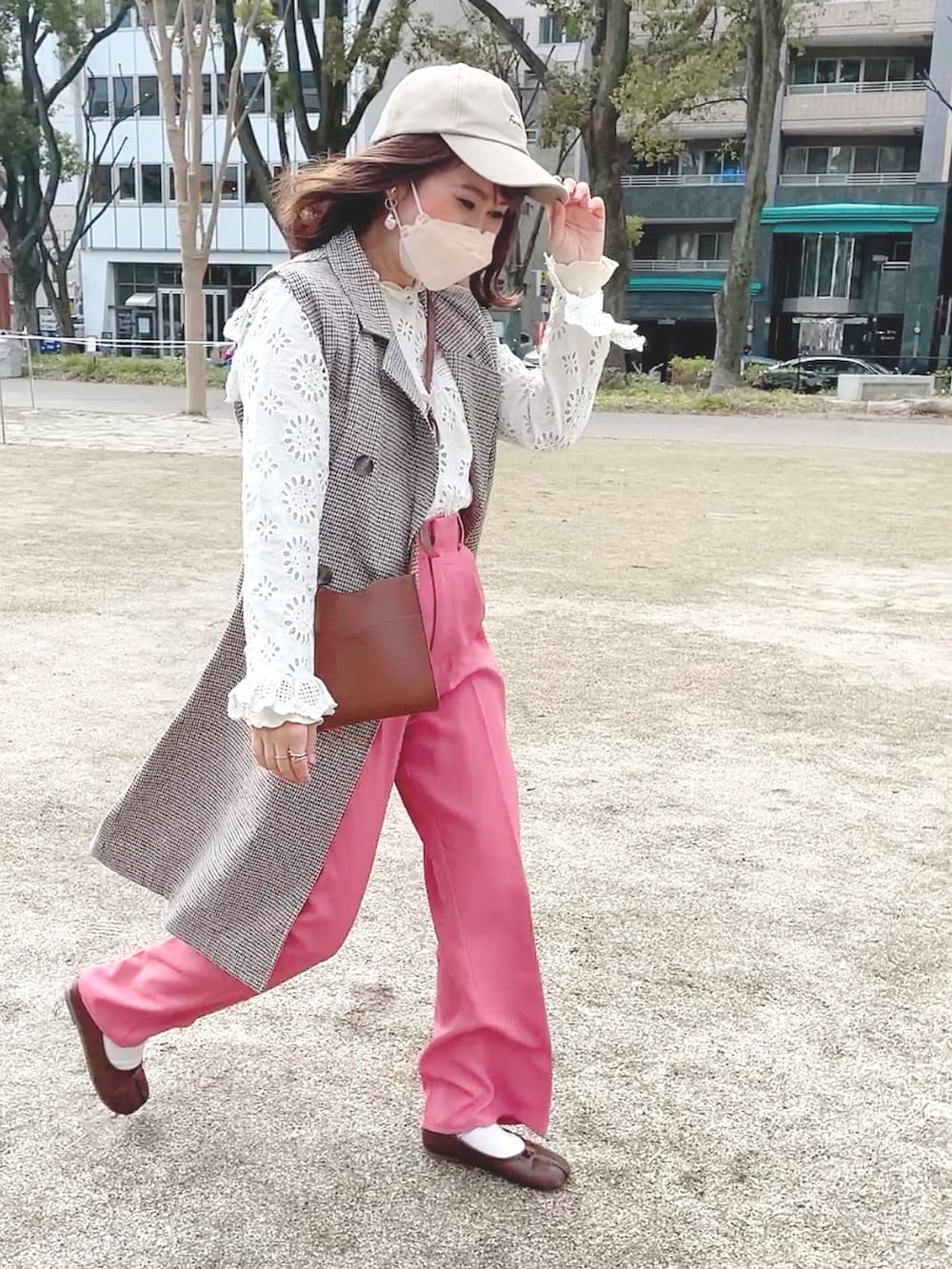 ピンク系のスラックス、ホワイト系のシャツ/ブラウス、ベージュ系のトレンチコートを着用したレディースの春コーディネートの2枚目の写真