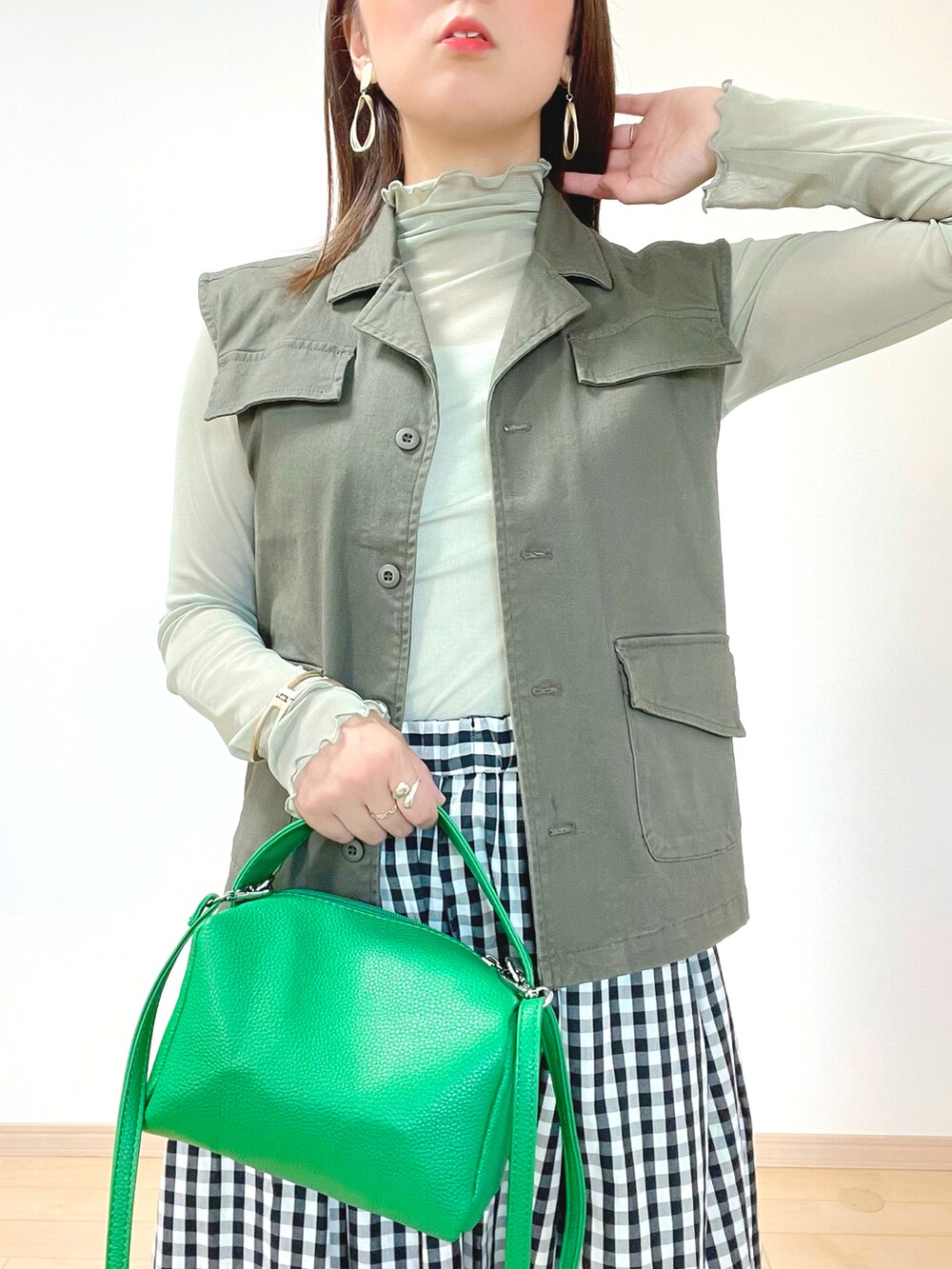 グリーン系のベスト、グリーン系のトップス、ブラック系のスカートを着用したレディースの夏コーディネートの4枚目の写真