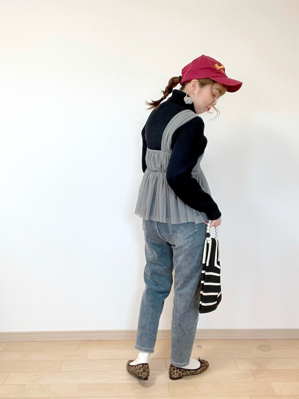 グレー系のキャミソール、ホワイト系のニット/セーター、グレー系のデニムパンツを着用したレディースの冬コーディネートの2枚目の写真