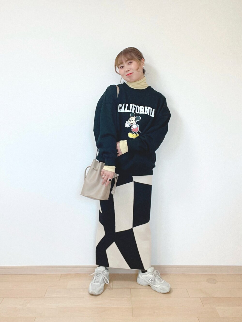 ブラック系のスウェット、イエロー系のトップス、ブラック系のスカートを着用したレディースの冬コーディネートの2枚目の写真