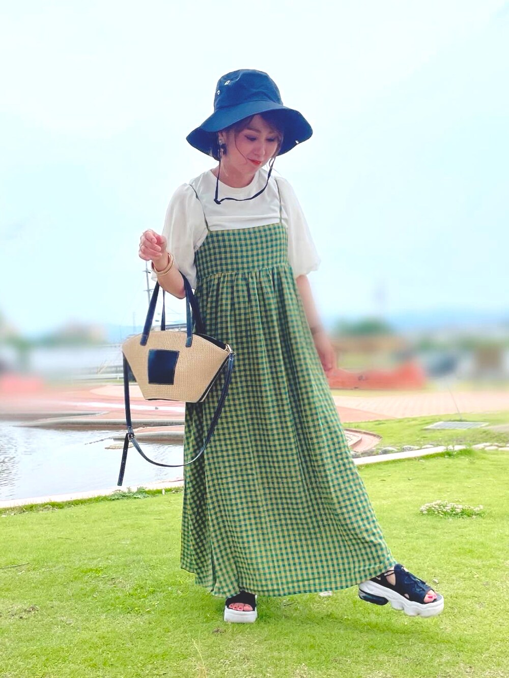 グリーン系のワンピース、ブラック系のサンダル、ブラウン系のバッグを着用したレディースの夏コーディネートの3枚目の写真