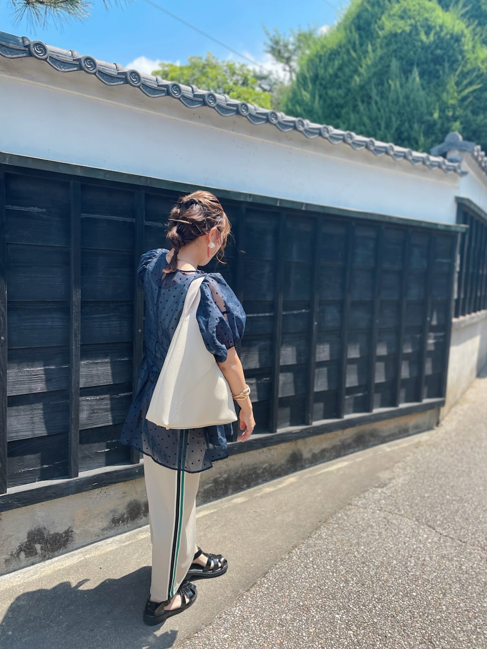 ブラック系のサンダル、ベージュ系のスカート、ホワイト系のバッグを着用したレディースの夏コーディネートの3枚目の写真